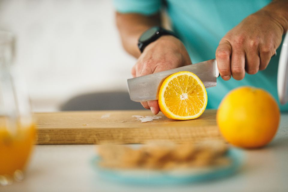 Hands slicing an orange on a kitchen counter